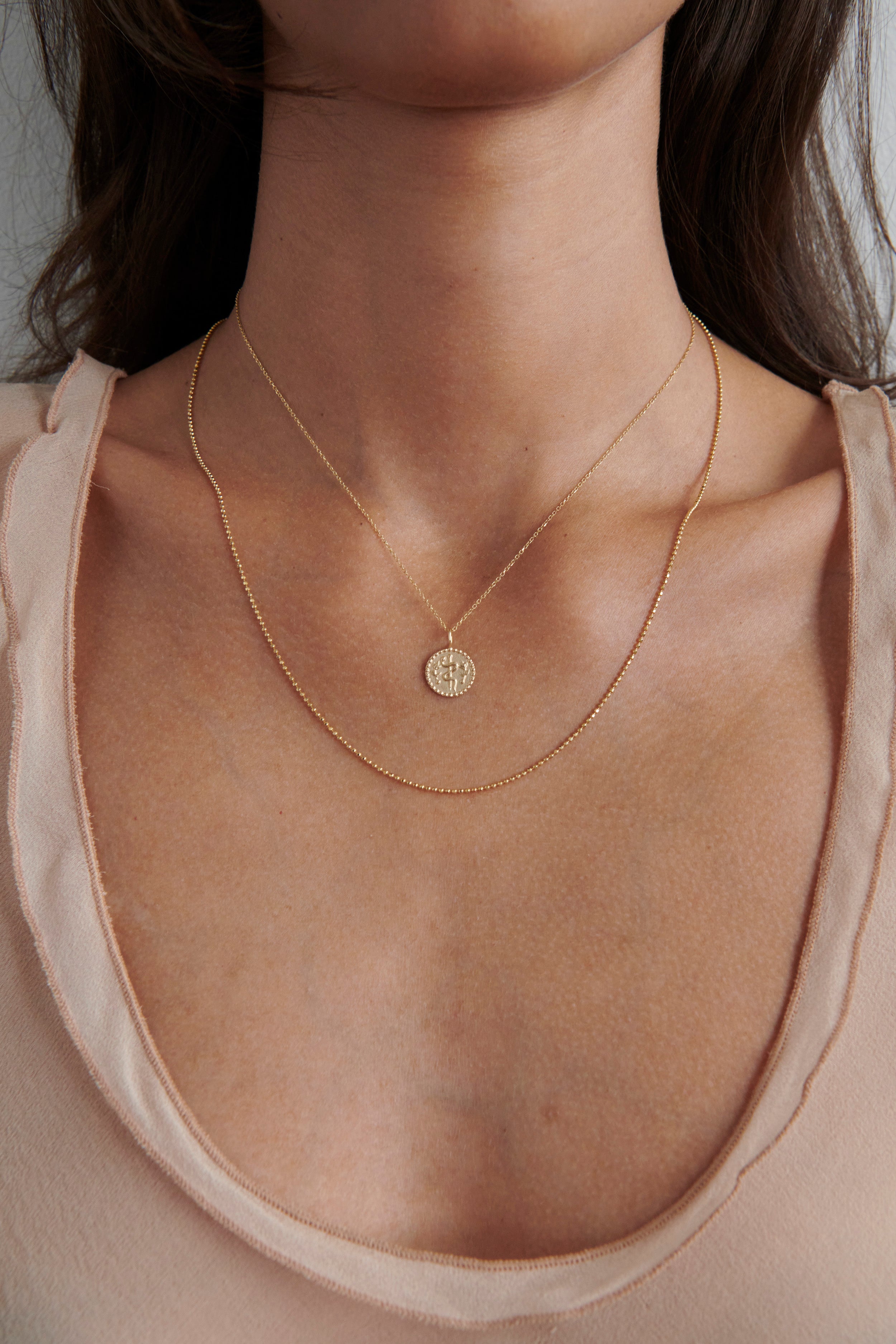 Close-up of Model Wearing Vale Jewelry Health Medallion Necklace with Faceted Bead Chain Necklace