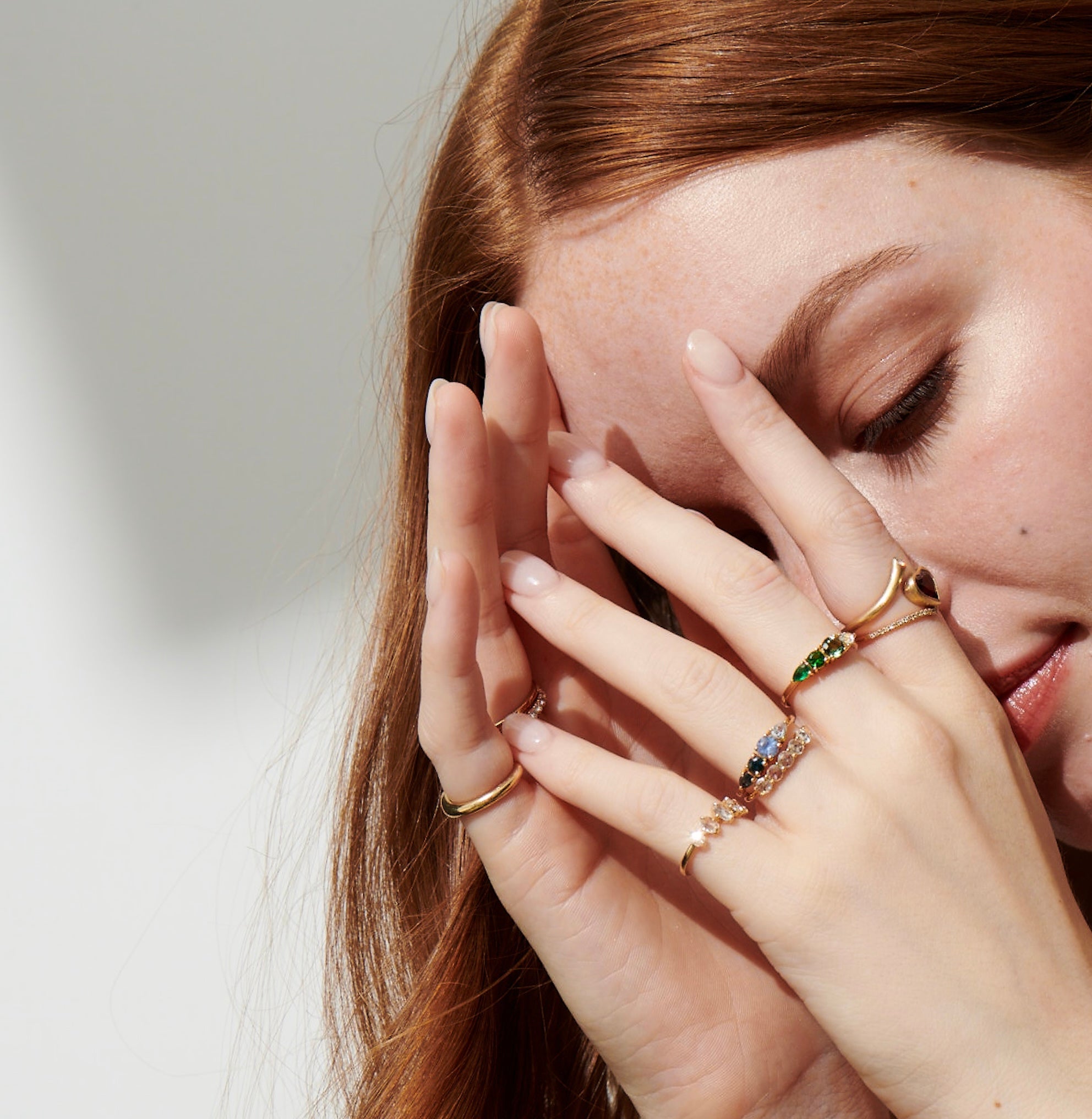Model Wearing Nadine Ring on Pinky and Garnet Heart and Diamond Twist Ring, Harmony Ring with Blue Sapphires, Harmony Ring with Green Gems and Roselle Ring with White Rose Cut Diamonds