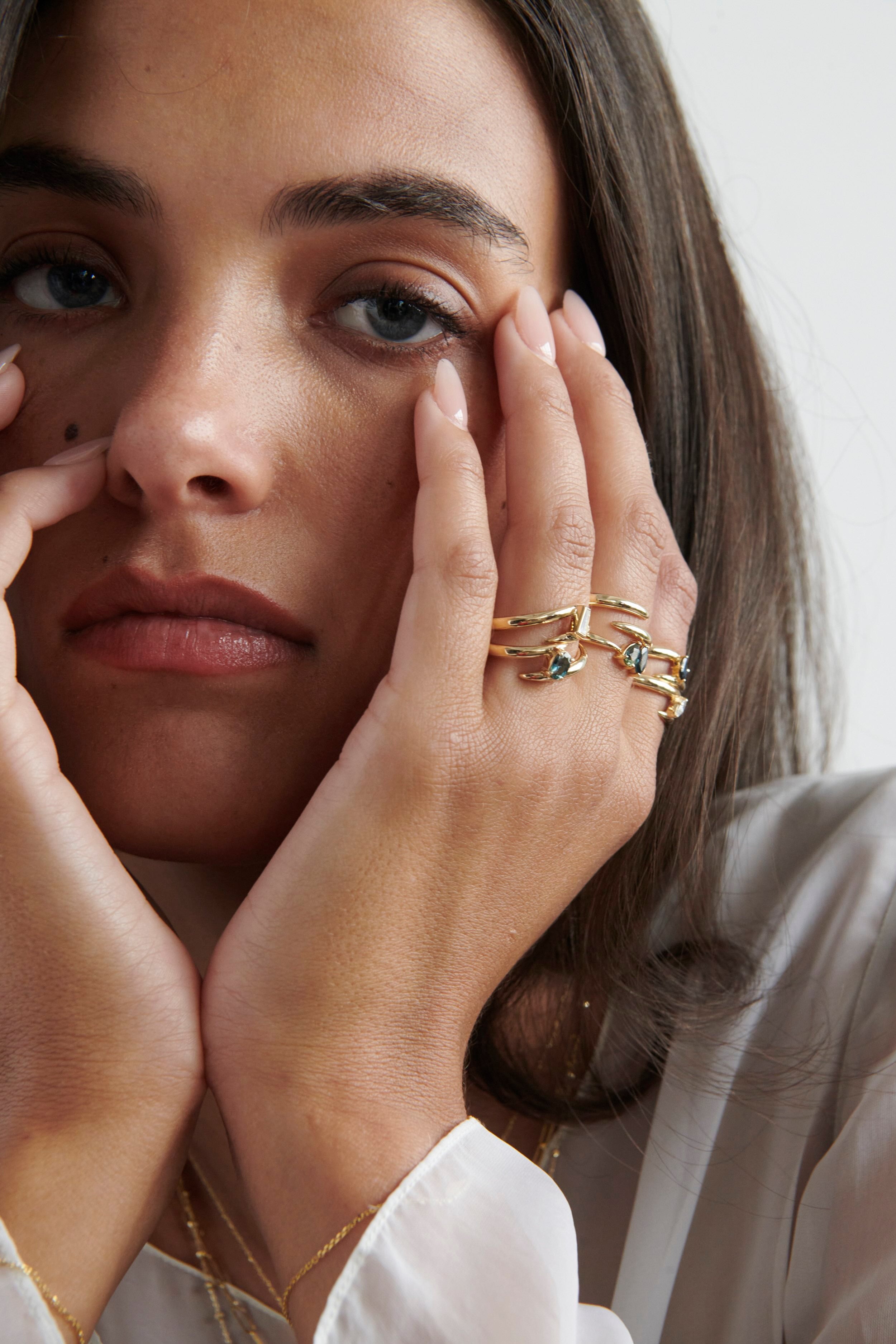 Close-up of Model Wearing Vale Jewelry Swoop Oval Cut Sapphire Bypass Ring with Multiple Gold Rings
