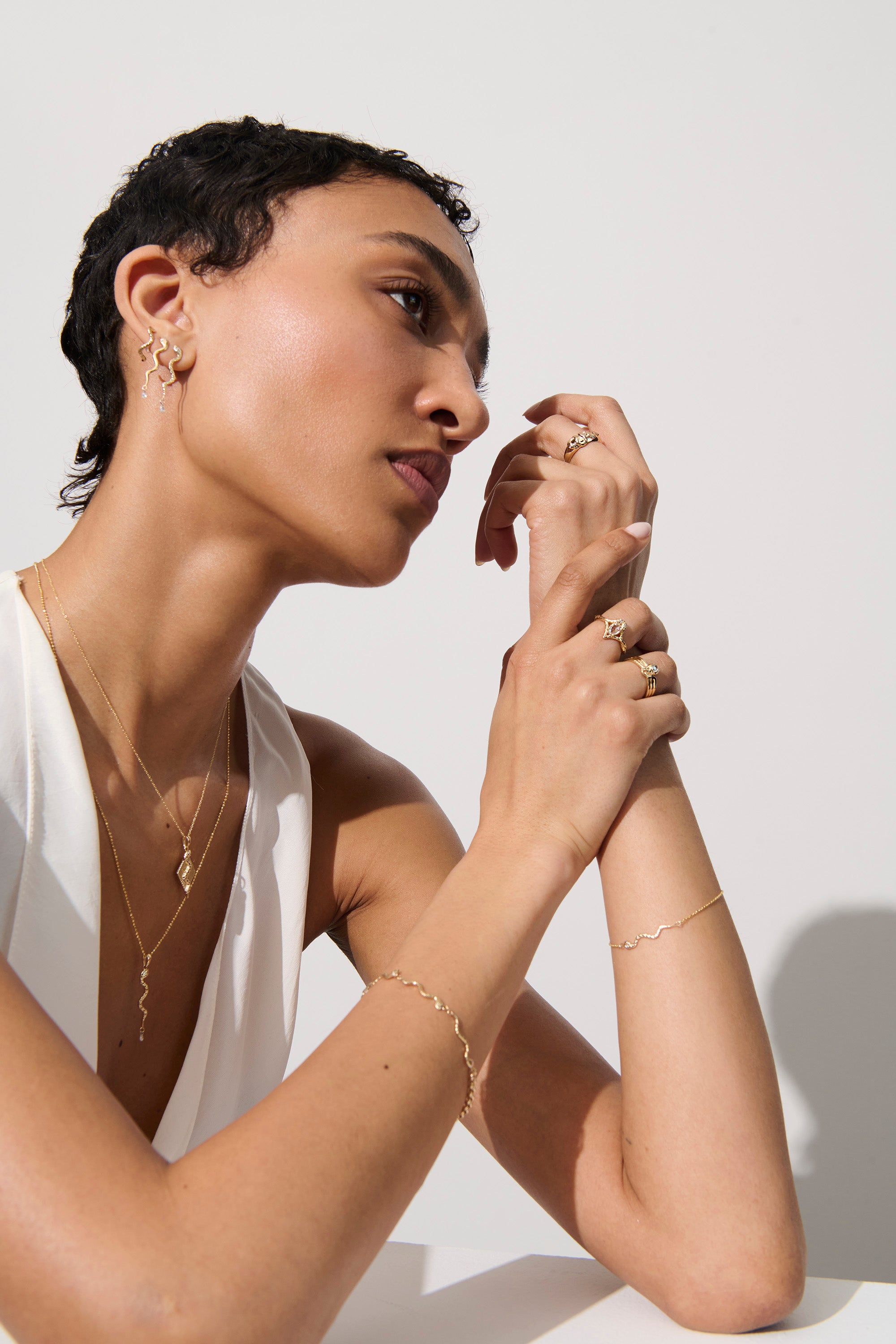 Alt="Vale Jewelry model in profile with hands up towards her face wearing gold domed serpent ring"