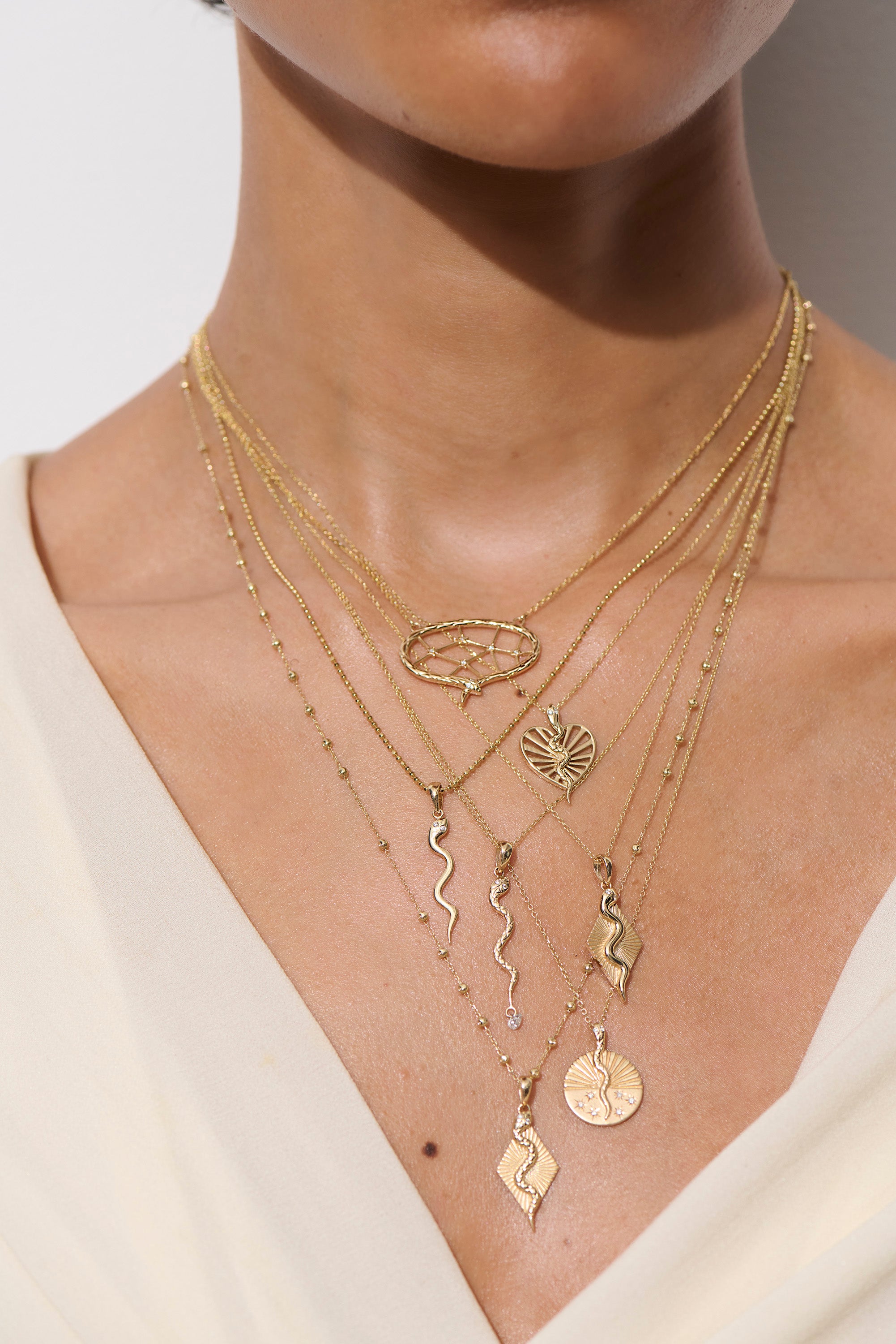 Alt="Vale Jewelry Close up of model wearing serpent necklace, textured serpent necklace with diamond drop, web of stars necklace, serpent ray necklace"