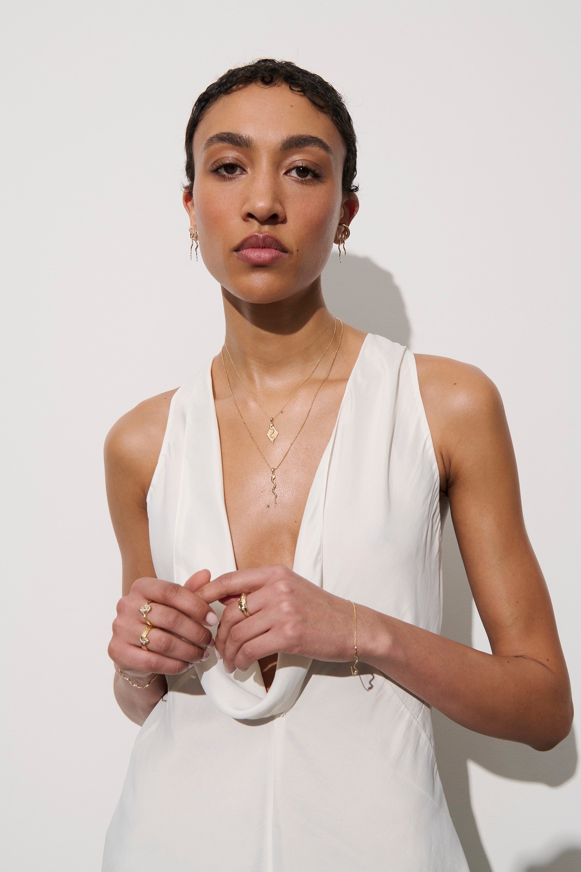 Alt="Vale Jewelry model in wide shot looking at camera wearing bracelets and other jewelry"