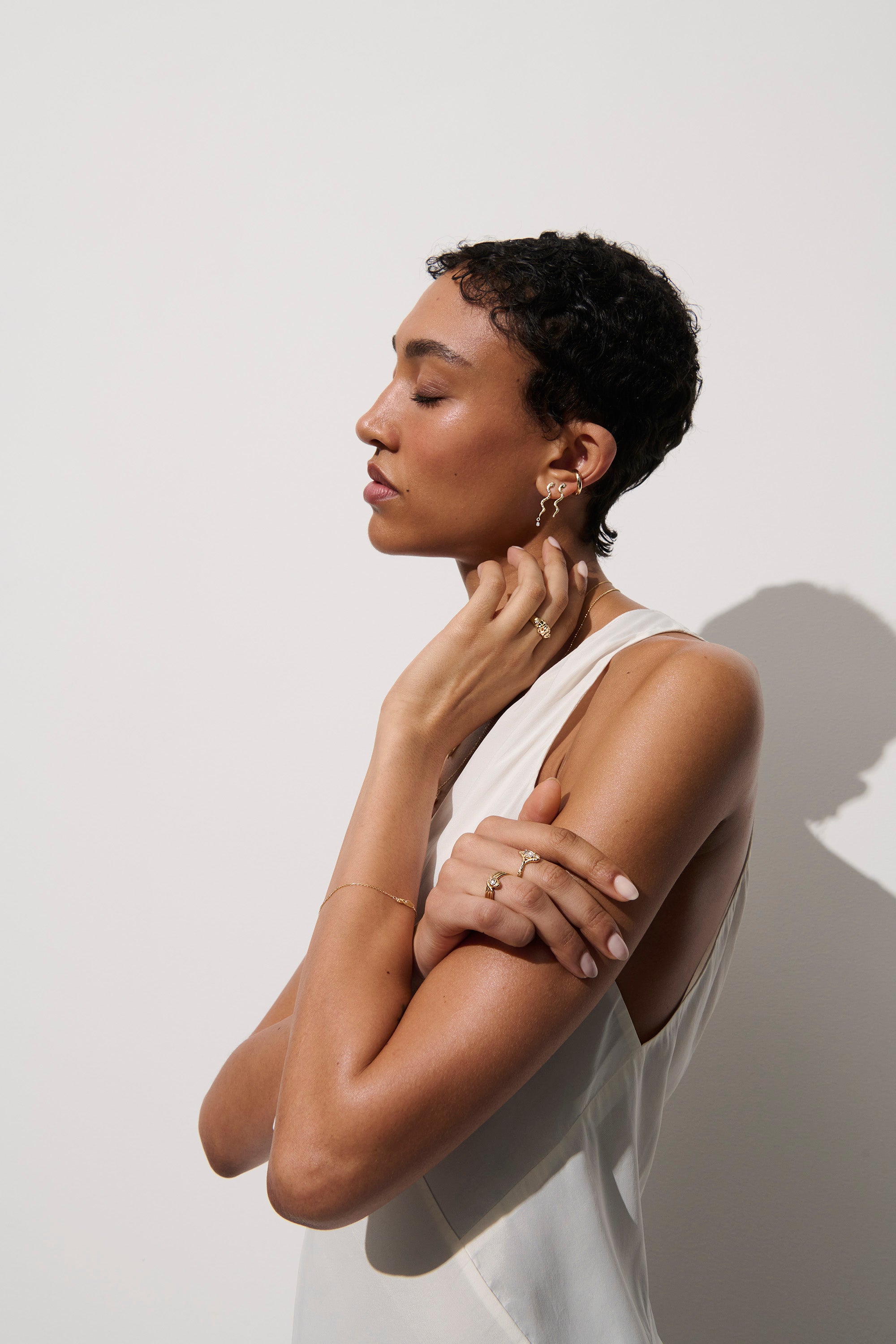 Alt="Vale Jewelry model wearing textured serpent earrings with diamond drops and gold domed serpent ring"