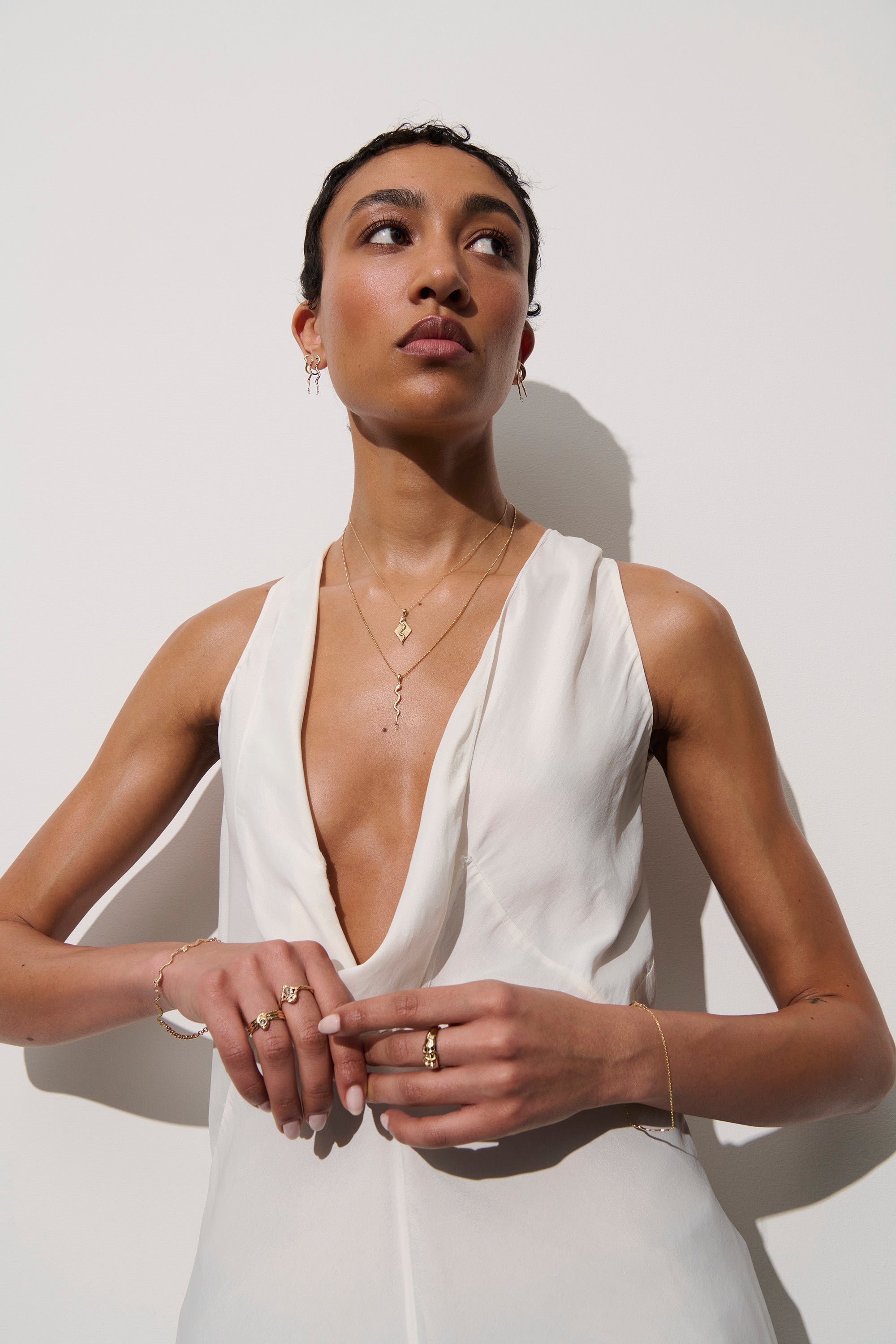 Alt="Vale Jewelry textured serpent earrings on model with other jewelry"