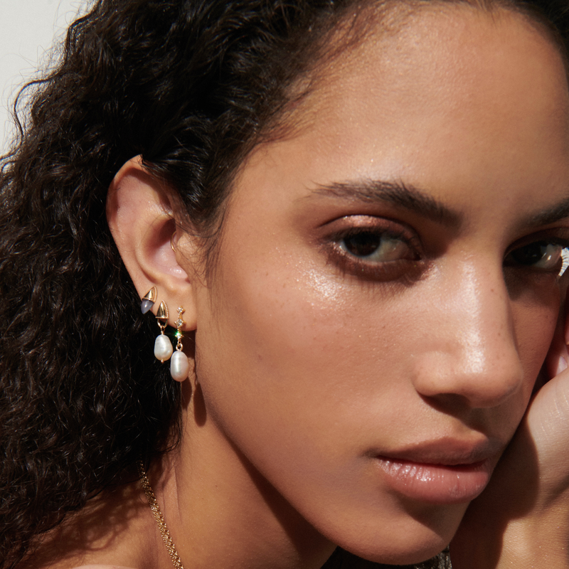 Model wearing the Amphora Lock Earrings with Pearls in Yellow Gold. They dangle lightly from the lobe.