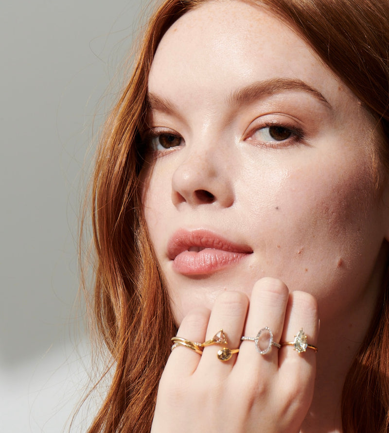 Close up of Model Looking Straight with Left Hand on Chin Wearing 4 Diamonds Rings Including Toi et Moi Champagne Diamond Ring, 1.88 Carat Rose Cut Diamond Ring, 1.50 Carat OOAK Step Cut Pear Solitaire Diamond Ring from Vale Jewelry