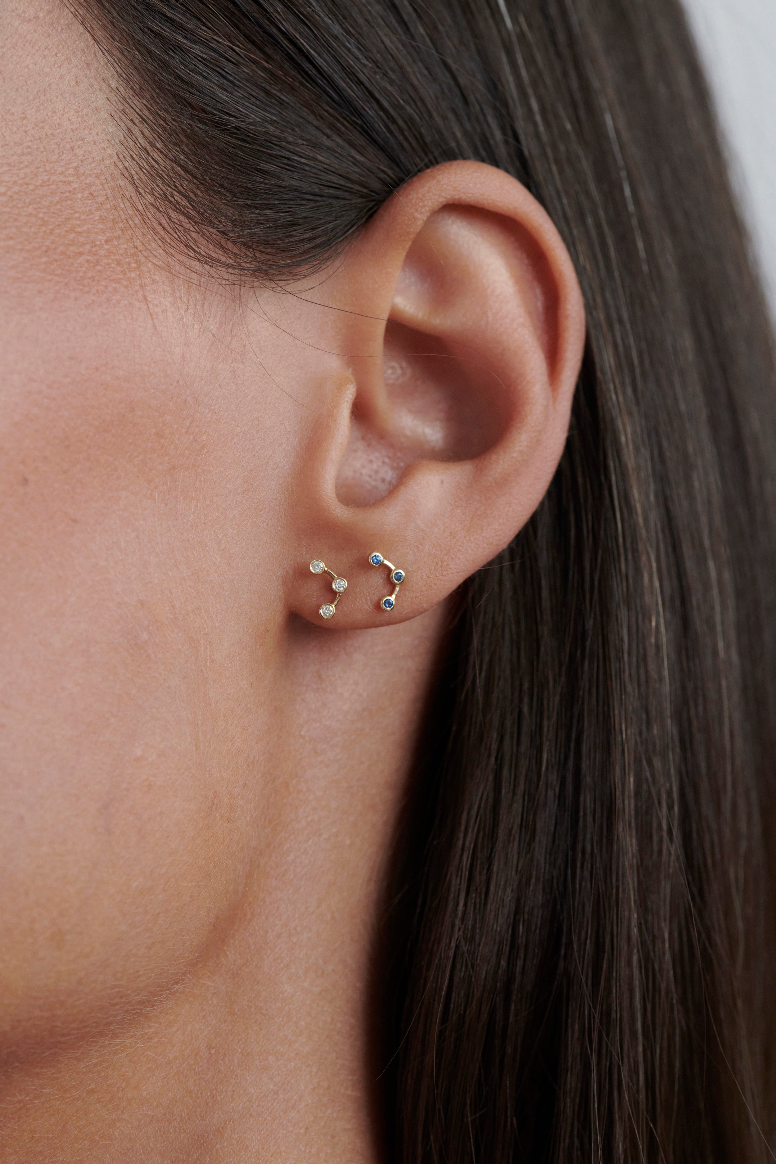 Close-up of Model Wearing Vale Jewelry Arc Earrings with White Diamonds and Arc Earrings with Blue Sapphires