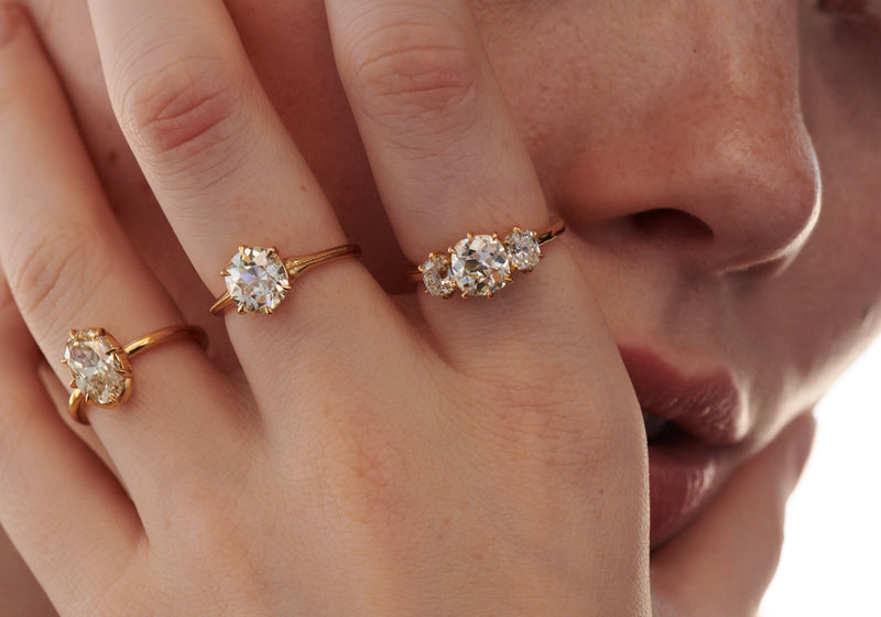 Close up of Model with Hand on Face Modeling 3 Diamond Rings Including 2.06 Carat Collet Set Ring, 2.09 Carat Old Mine Delilah Ring and 3-Stone Old Mine Ring from Vale Jewelry