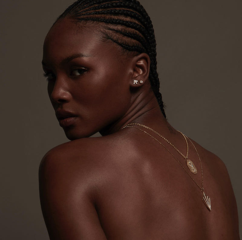 Model Wearing Larkspur Earrings with Baguette and Princess Cut Diamonds with Necklaces Draped on Back from Vale Jewelry 