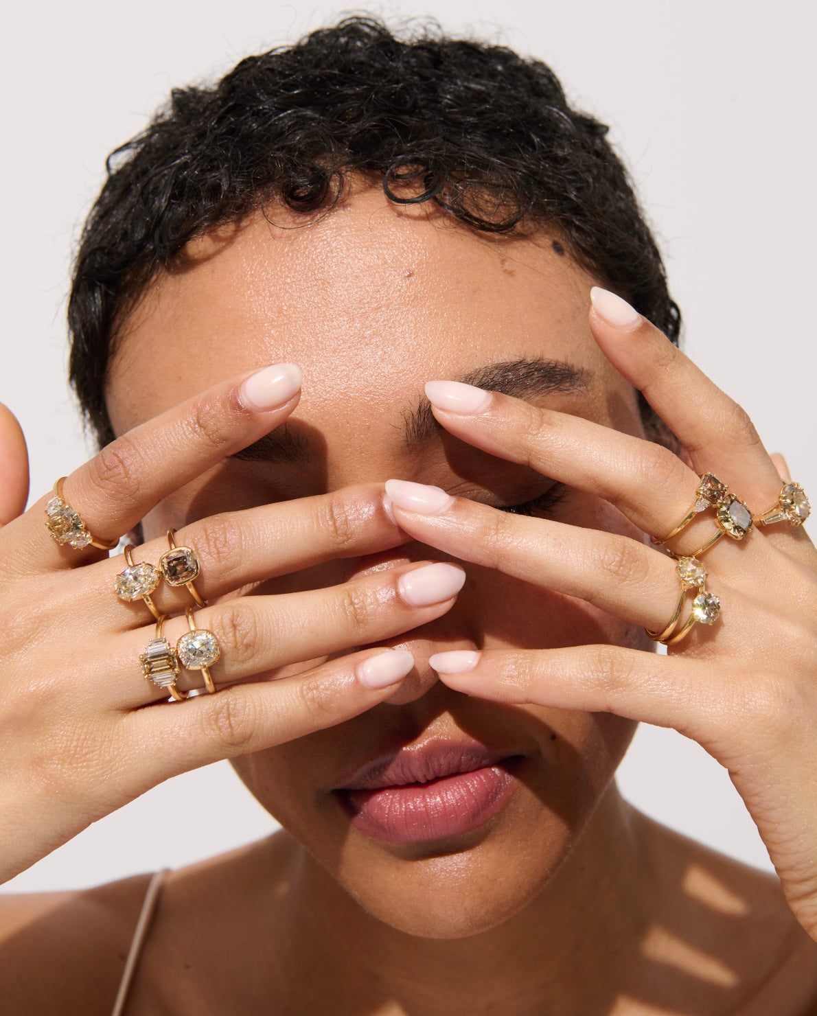 Model Wearing 2.06 Carat Zoe Collet Set Diamond Ring with Hands in Front of Face, Stacked with Other Brown Diamond Rings