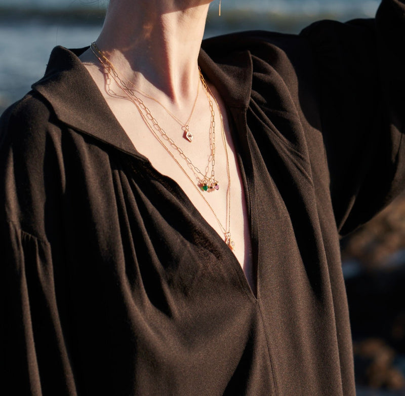 Model in Sunlight Wearing Small Fleche Necklace and Amphora Amulets with Amethyst, Green Onyx and Quartz from Vale Jewelry