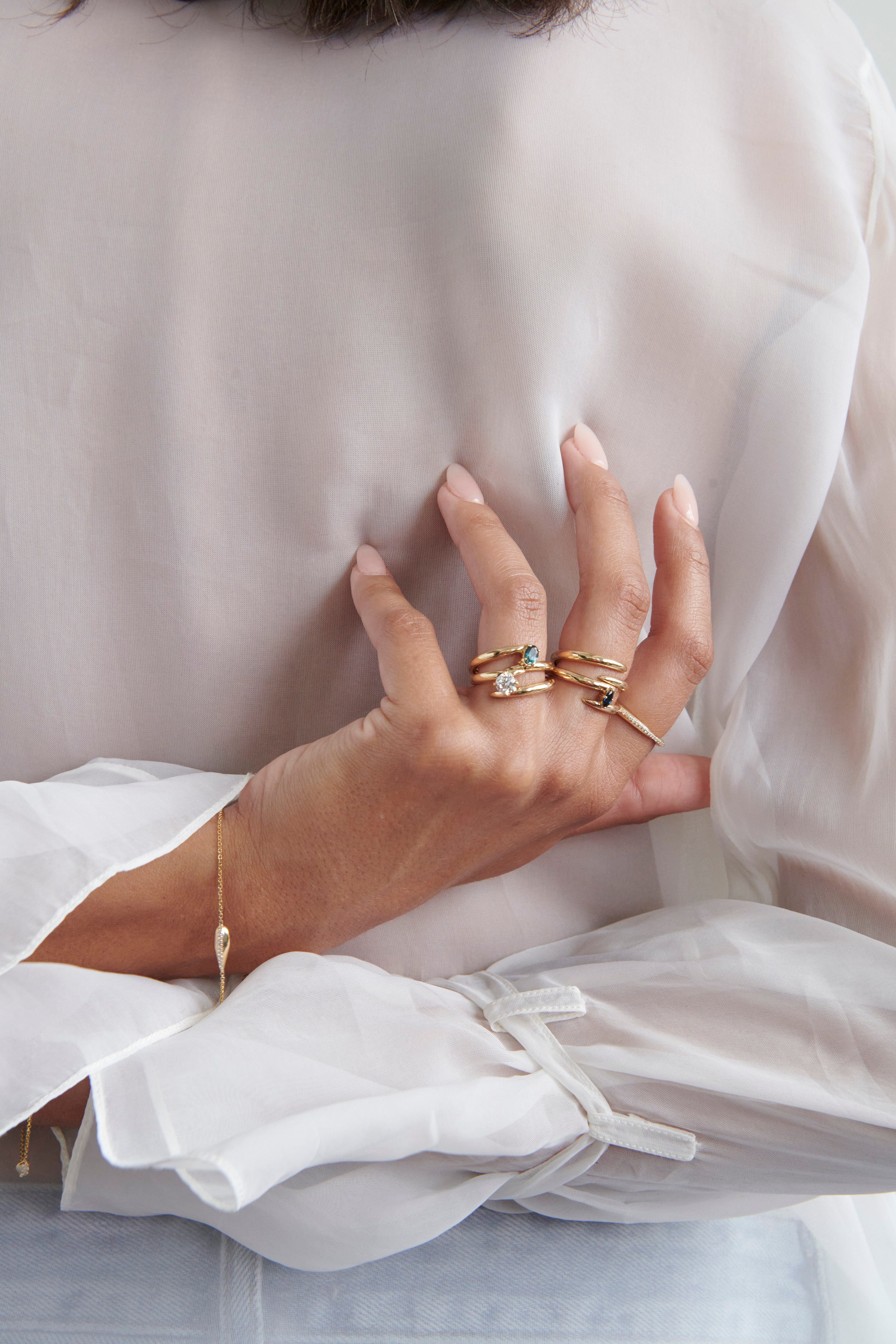 Close-up of Hand Model Wearing Vale Jewelry Swoop Bypass Ring with Multiple Gold Rings