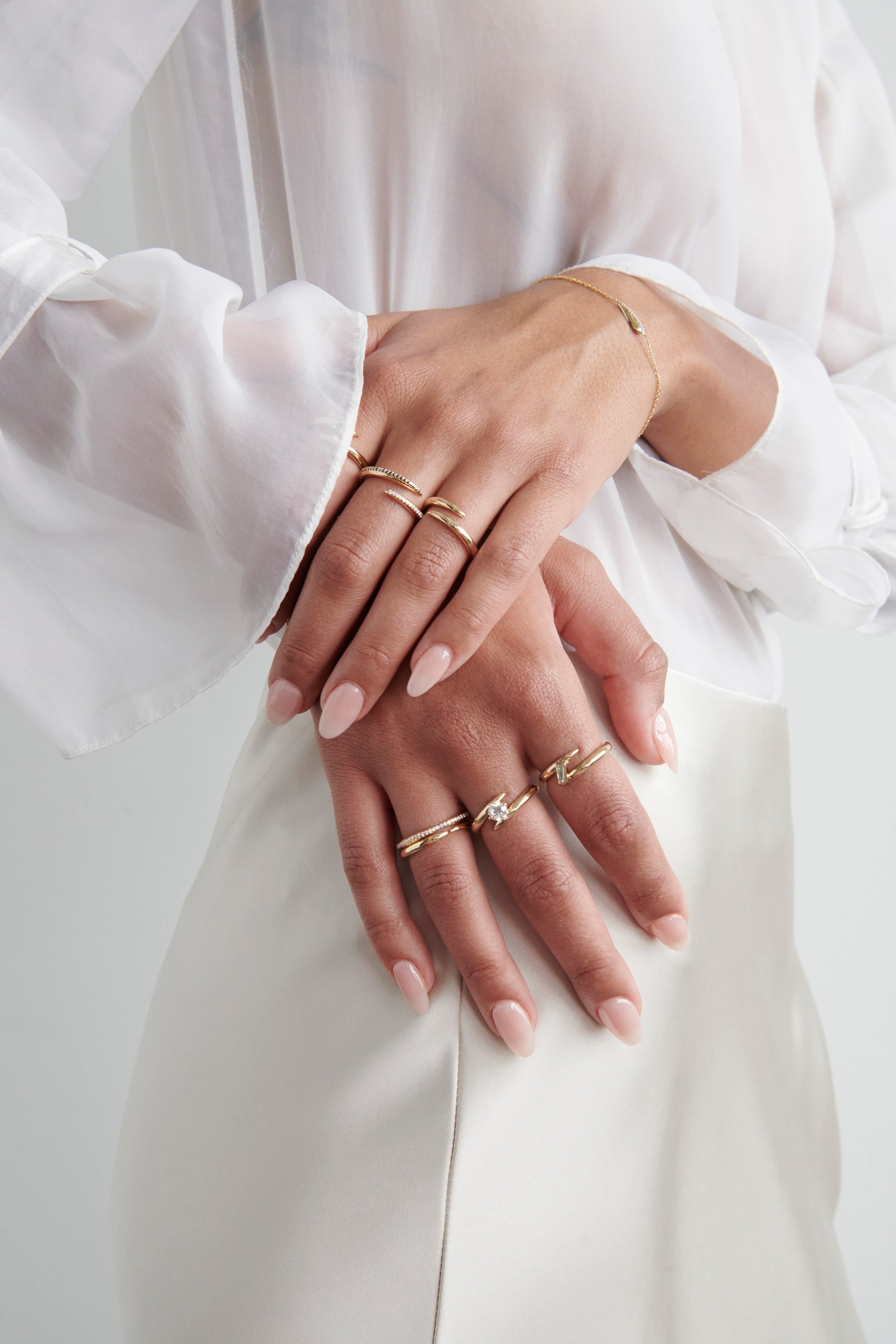 Close-up of Hand Model Wearing Vale Jewelry Swoop Bypass Ring with Multiple Gold Rings