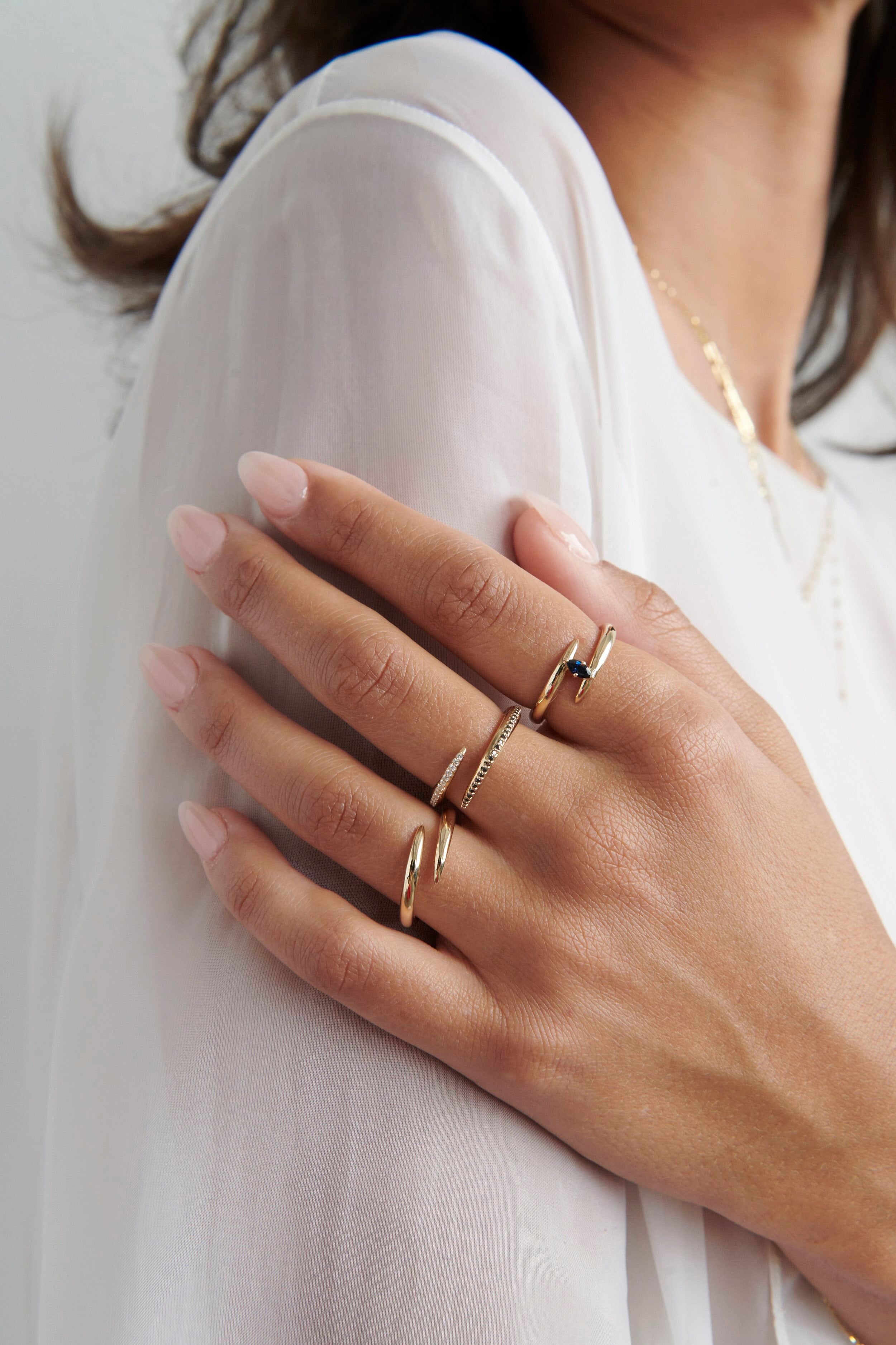 Close-up of Hand Model Wearing Vale Jewelry Swoop Bypass Ring with Multiple Gold Rings