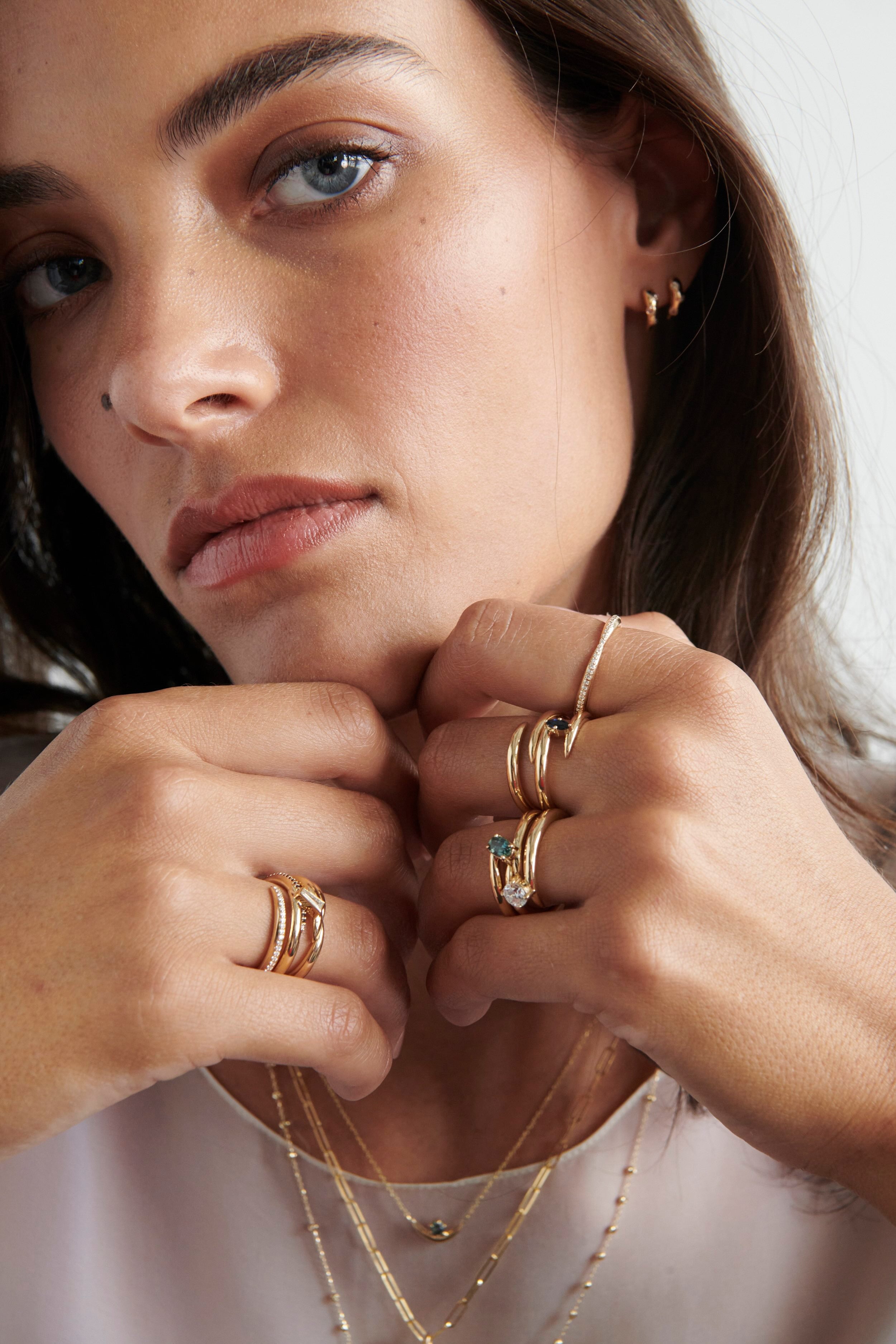 Close-up of Model Wearing Vale Jewelry Swoop Oval Cut Sapphire Bypass Ring with Multiple Gold Rings