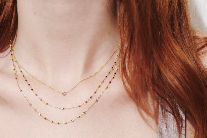 Close up of Model Wearing Two Rosary Necklaces Layered With Bezel Set Barely There Diamond Necklace from Vale Jewelry