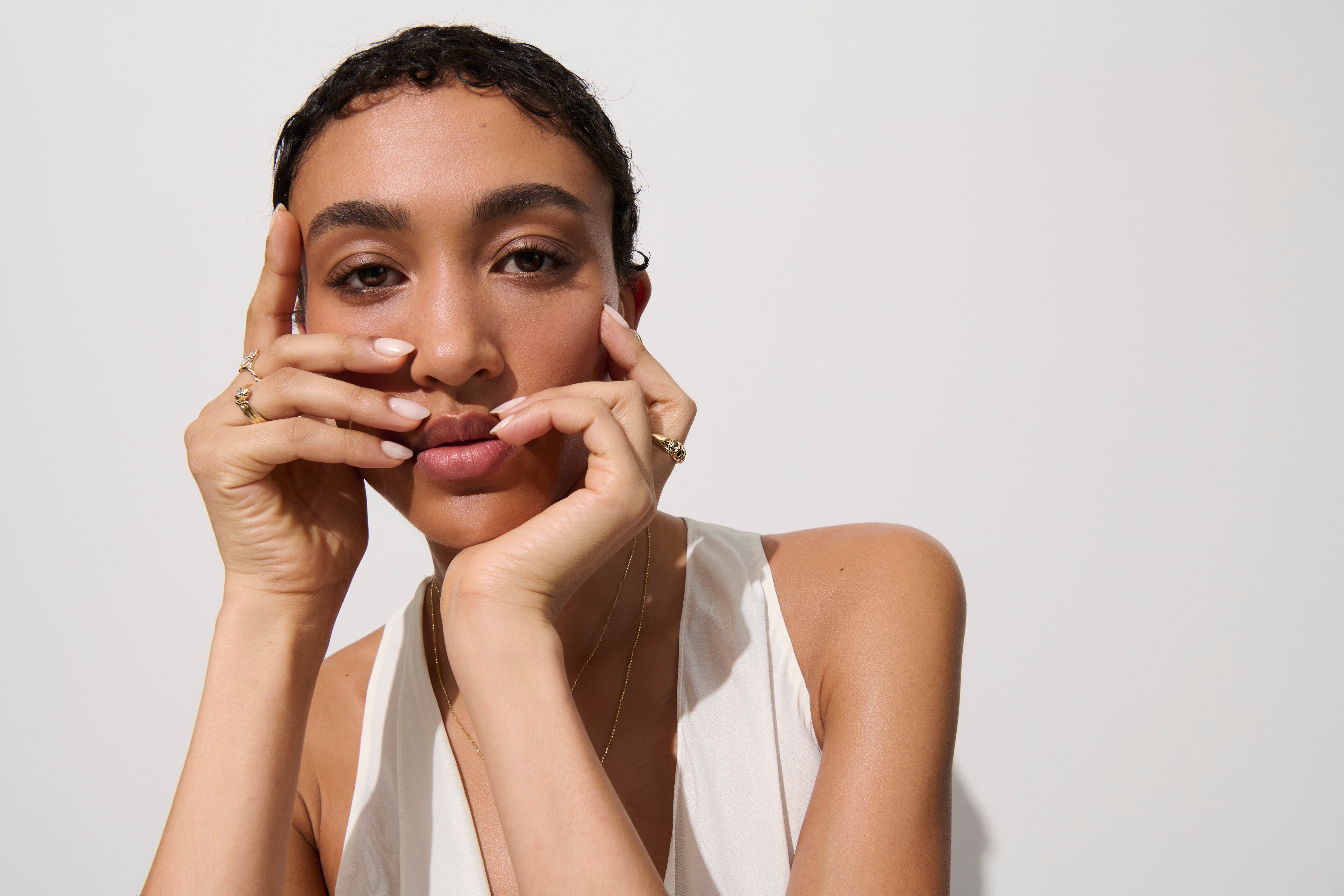 Alt="Vale Jewelry model posing with gold domed serpent ring with hands by her face"