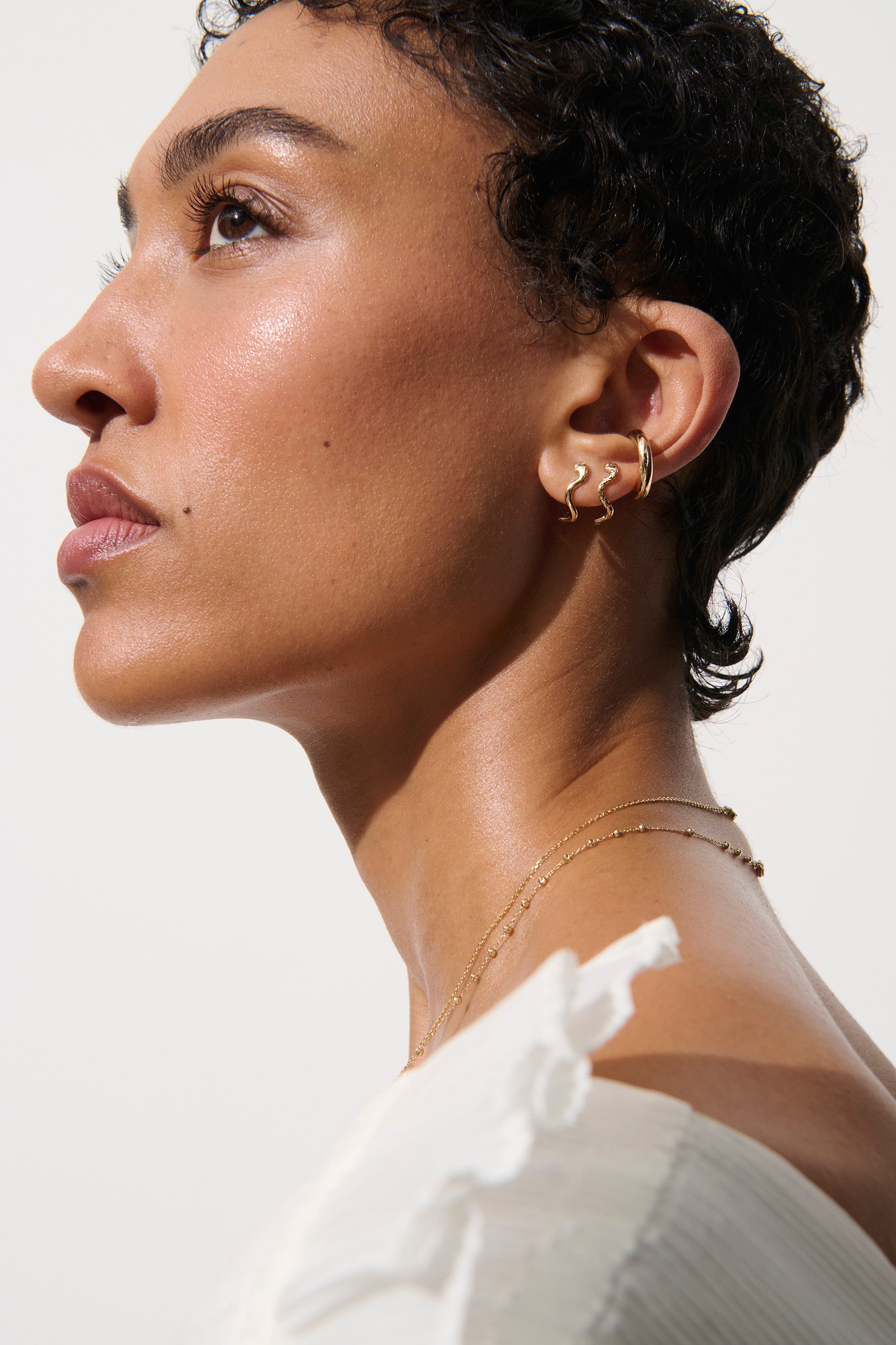 Alt="Vale Jewelry textured serpent half hoops on model in profile"