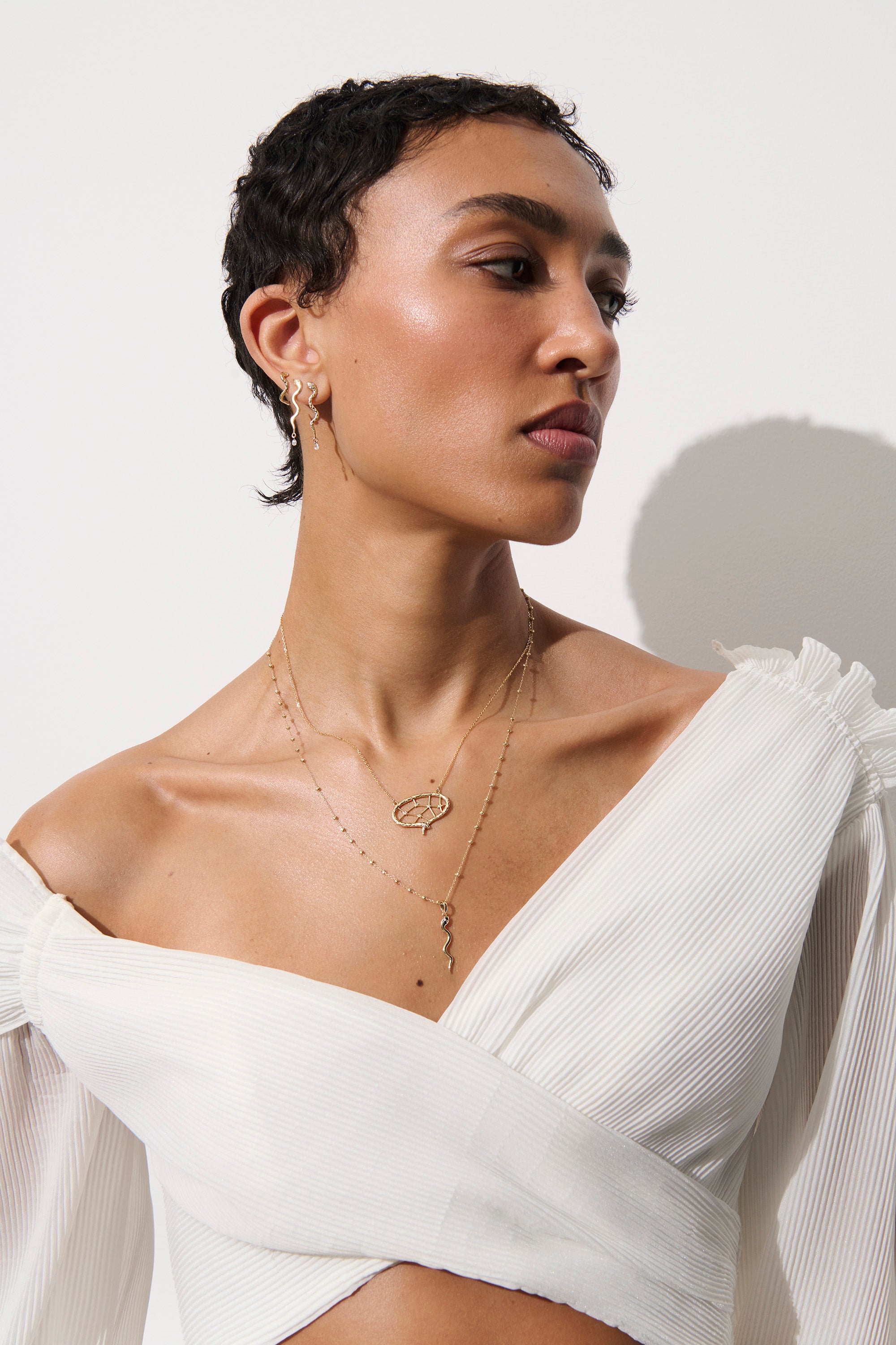 Alt="Vale Jewelry textured Serpent Half Hoop Earrings and serpent necklace on Model wearing white top"