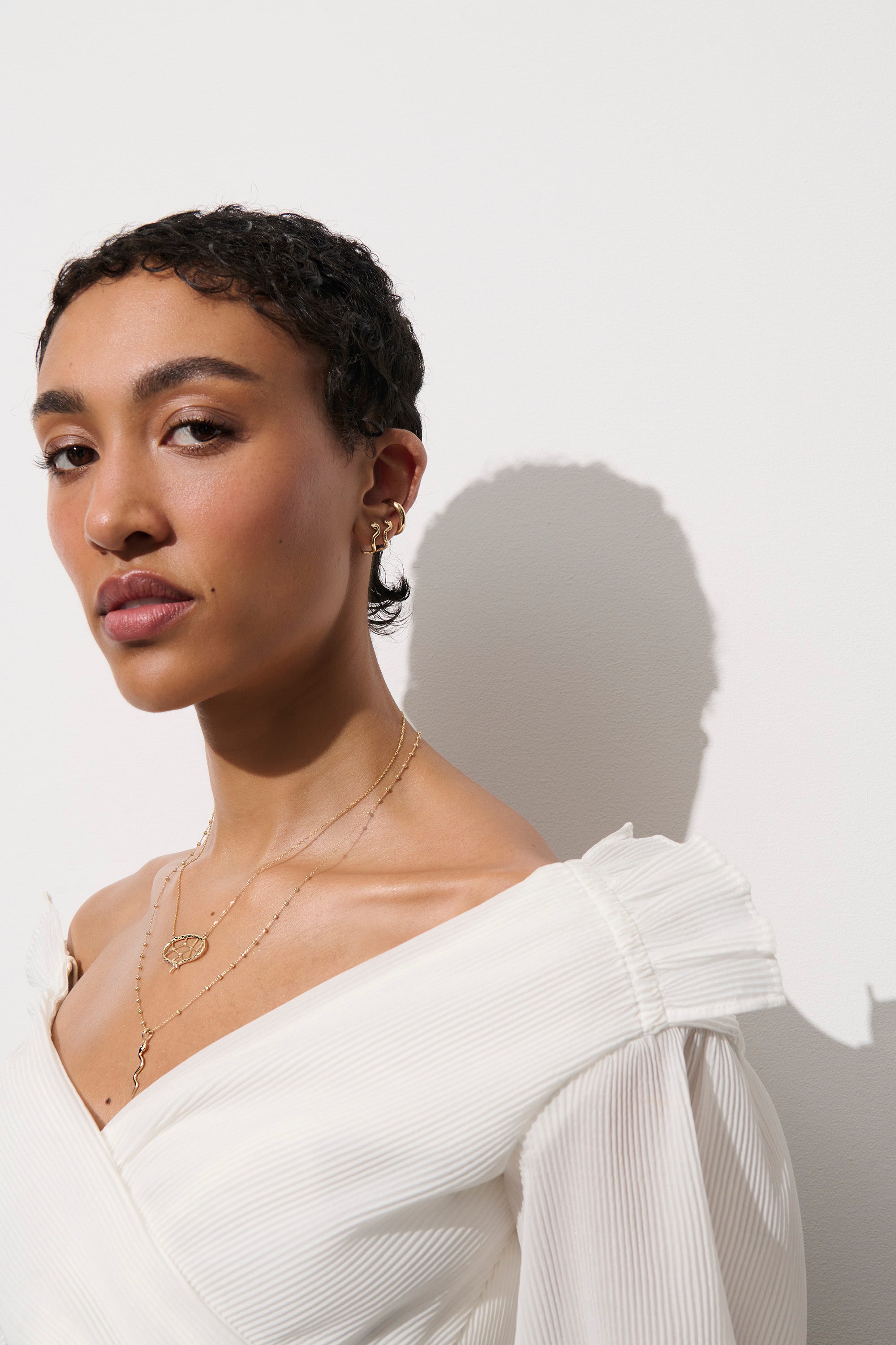 Alt="Vale Jewelry model wearing web of stars necklace in a white top facing to the side"